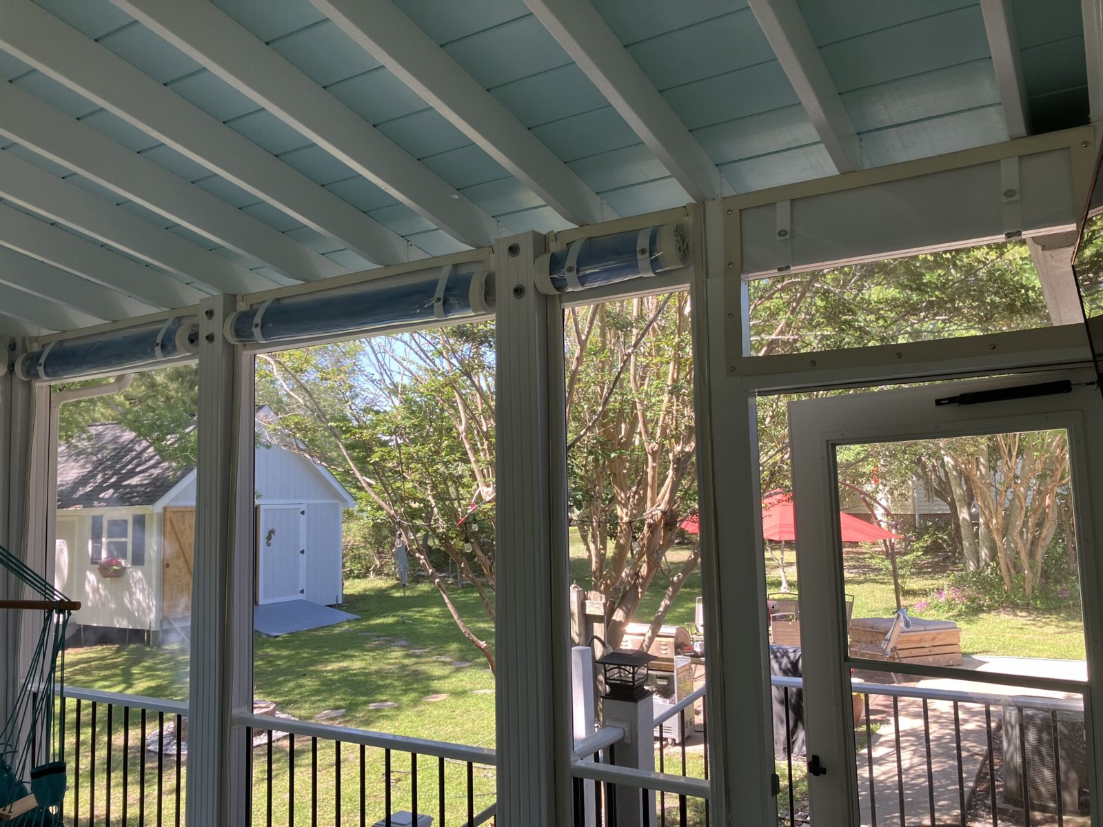 Hand roll-up clear vinyl curtains enclosing a screened porch