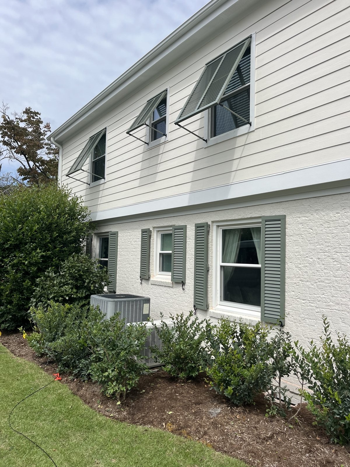 Bahama shutters mounted above coastal home windows