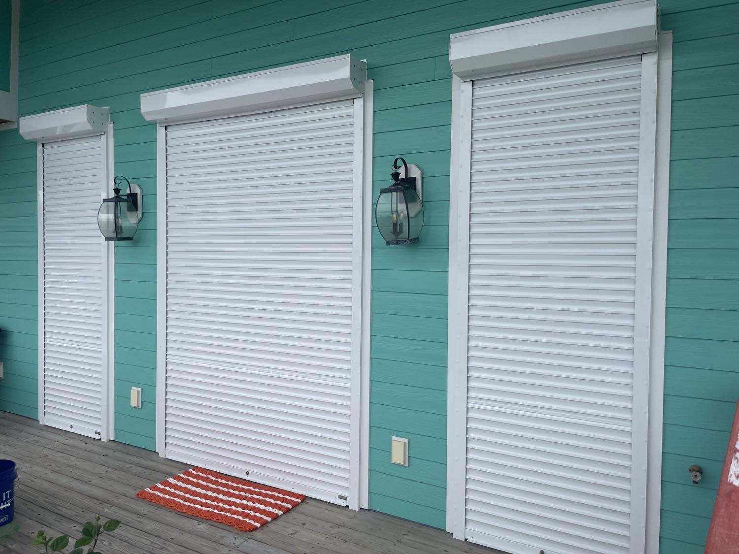 White motorized roll shutters closed over coastal home windows