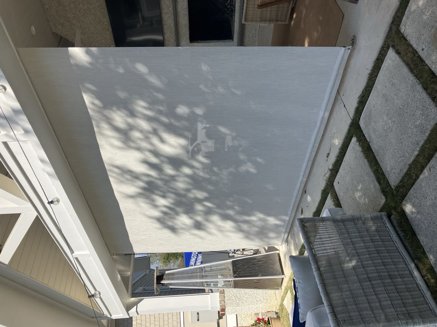Rolling shade curtain lowered along a covered porch